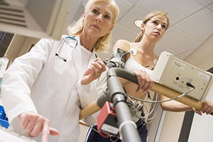 Picture of young woman on a treadmill performing a stress test under the supervision of a doctor.